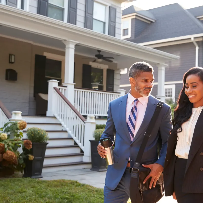 Business Couple Leaving Suburban House For Commute To Work
